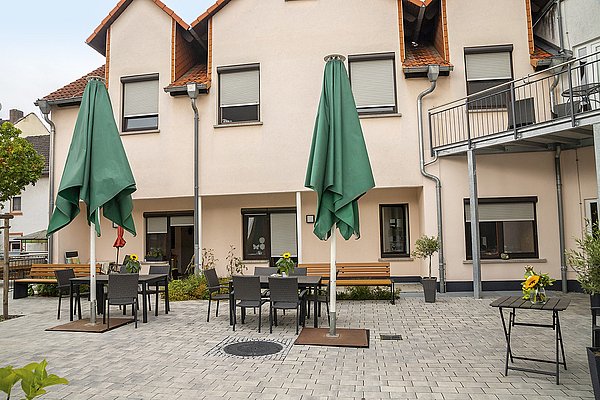 Gepflasterter Hof des Haus Ysenburg mit großen Sonnenschirmen und mehreren Sitzgelegenheiten